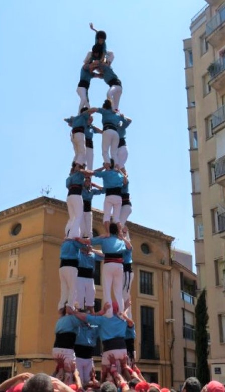 A "human tower" - a team dressed in blue tops and white pants stands on each other's shoulders to form a tall tower.