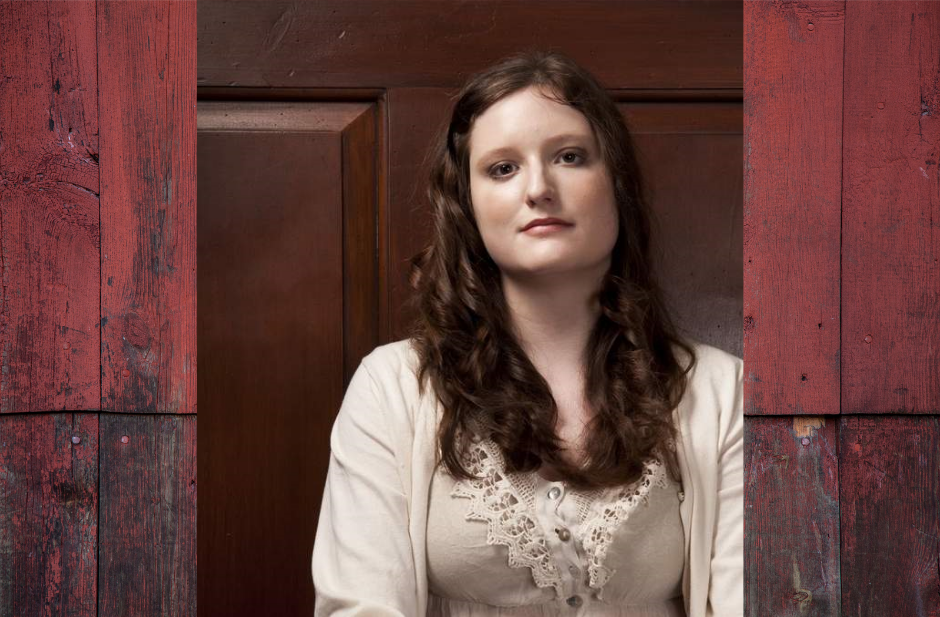 Alix Generous leaning on a dark brown door.