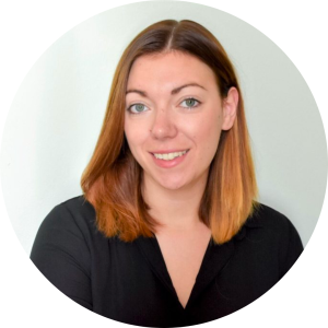 woman smiling at the camera in a black top with brownish-orange hair.
