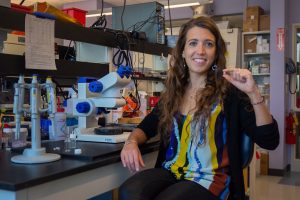 Dr. Ester Caffarel-Salvador is in a lab holding a prototype of the insulin pill she developed.