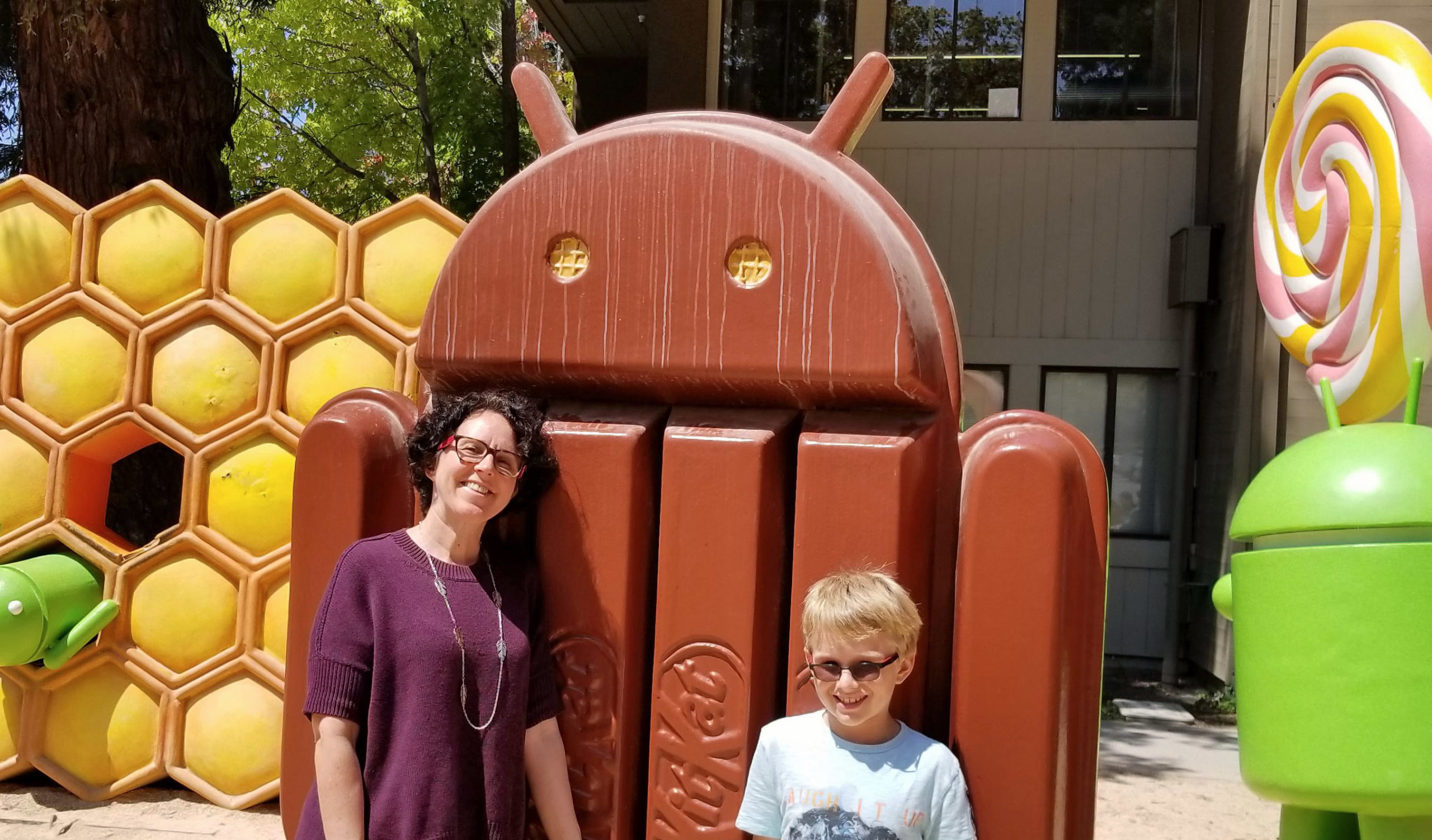 Cathy Pearl standing in the colorful Google Android statue garden with her son.