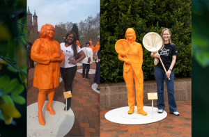 Two women scientists stand next to orange life-size statues of themselves outside the Smithsonian.