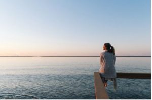 woman sitting on a pier looking out over the ocean