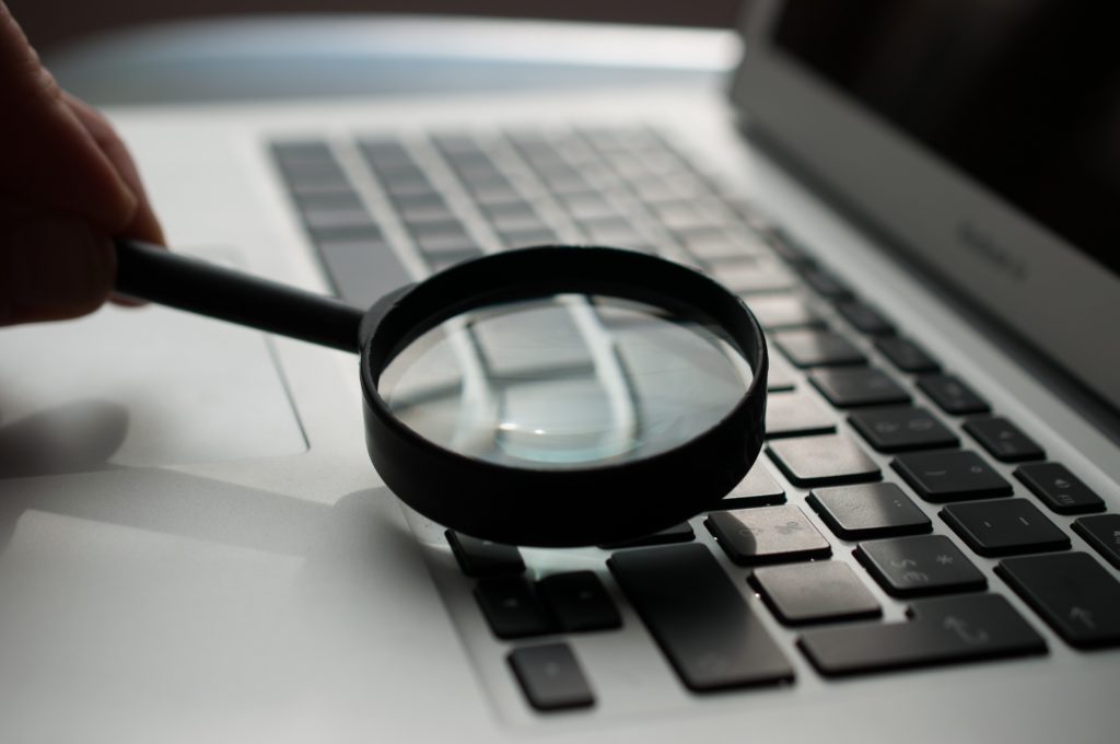 Photo of a magnifying glass held over a laptop keyboard