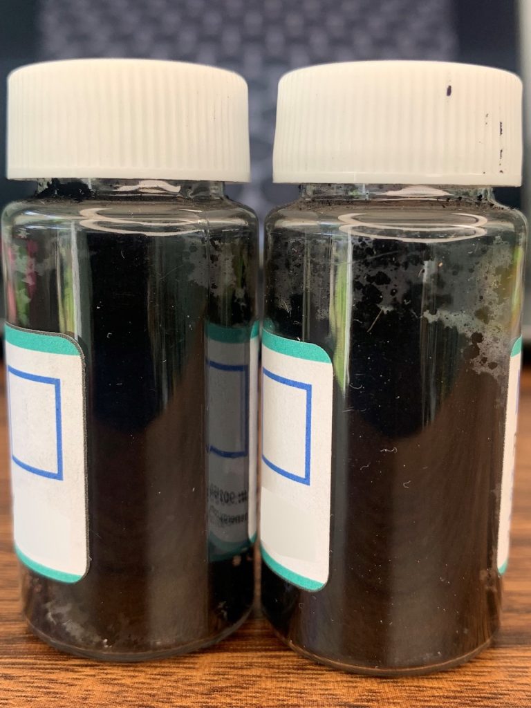 Two clear bottles side-by-side, filled with black flakes.