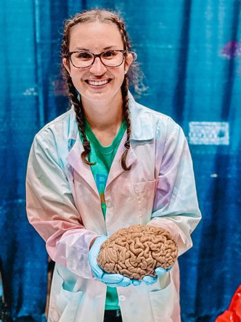 AWIS member Kimberly Fiock in a lab coat holding a human brain