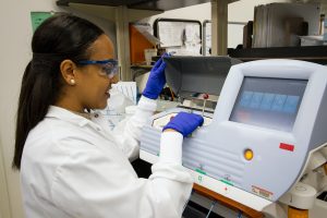 A technician loads DNA samples into a desktop genomic sequencing machine
