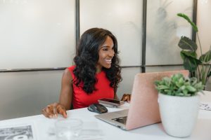 A woman smiles looking at a laptop in a sleek office setting